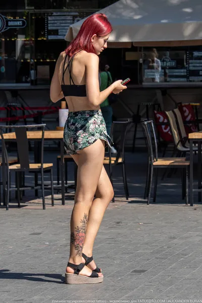 Lány egy tetoválás piros virág alján a jobb lábát — Stock Fotó