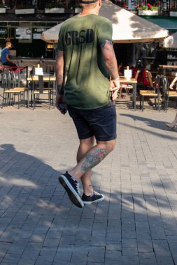 Bacağında dövme baltası, kolunda dövme hiyeroglifleri olan adam.