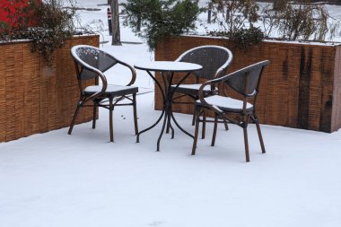 Karla kaplı sandalyeler ve küçük bir kafe masası. Kışın kafe mobilyaları.