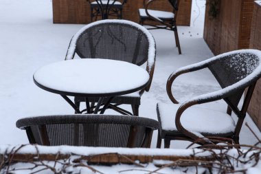 Karla kaplı sandalyeler ve küçük bir kafe masası. Kışın kafe mobilyaları.