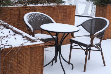 Karla kaplı sandalyeler ve küçük bir kafe masası. Kışın kafe mobilyaları.