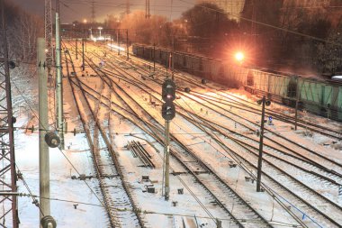 Geceleri büyük bir tersanenin karla kaplı rayları istasyonda duran kömürlü bir tren.