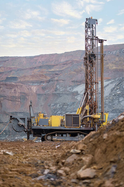 Large drill rig in an ore quarry. Preparation of boreholes for laying explosives in the quarry. Open-pit mining technologies.