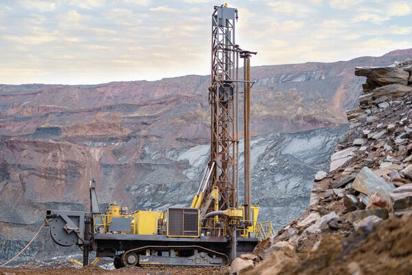 Large drill rig in an ore quarry. Preparation of boreholes for laying explosives in the quarry. Open-pit mining technologies.