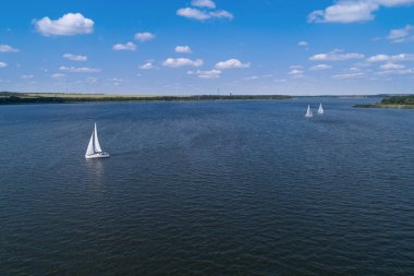 Güneşli bir günde, nehir yelkenli teknelerinde bozkır nehrinin havasından manzarayı seyret. Nehirde yelken sporları.