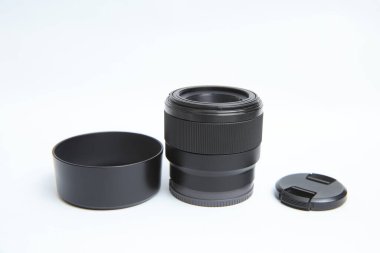 Beyaz zemin üzerinde küçük bir fotoğraf merceği kameradan ayrılır. Beyaz arka planda fotoğraf ekipmanları var. Lens kapakları ve lens kapağı ile mercekler tamamlandı.