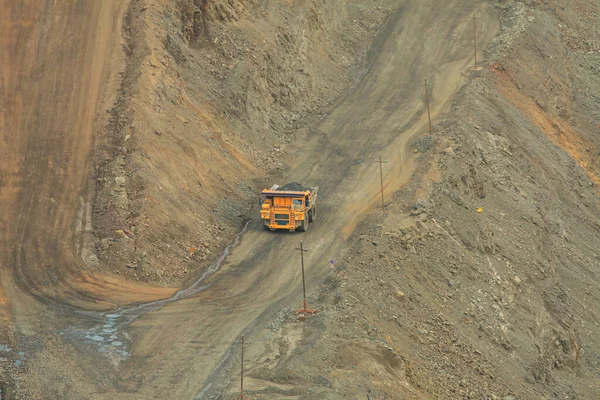 A mining dump truck loaded with iron ore moves along the serpentine of the quarry. The process of open-pit mining.