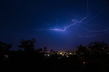 Şehrin üzerinde şimşekler çakıyor. Geceleyin bir yaz fırtınası.