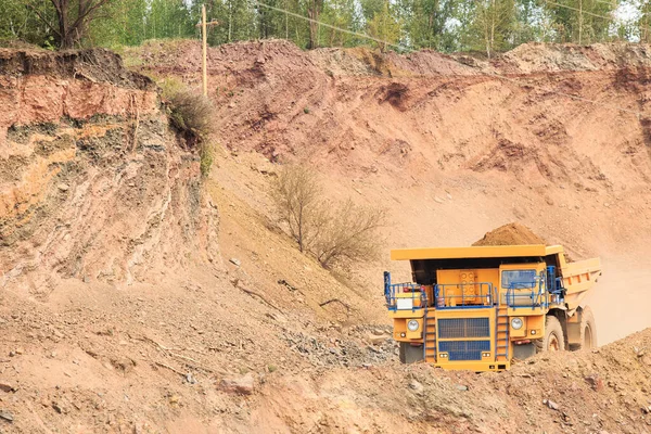 Large yellow quarry truck loaded with rock mass. The process of open-pit mining. The work of heavy industry machinery