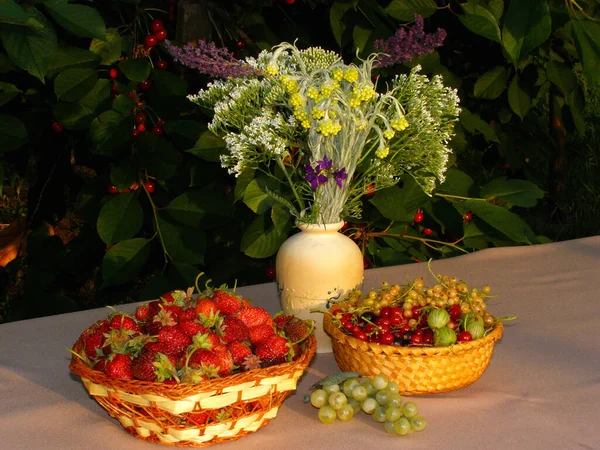 Table with a light tablecloth on the table berries and a bouquet of flowers in a vase