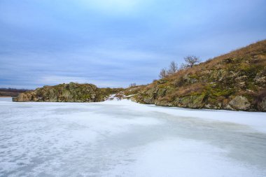 Bir nehrin ya da gölün donmuş suyu. Kıyının su tarafından dik uçurumlar ve uçurumlar manzaralı.
