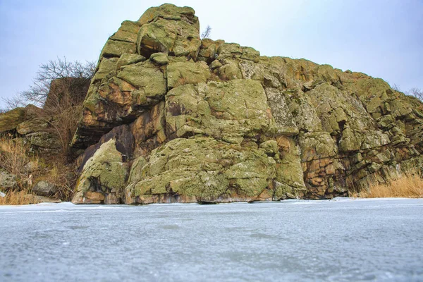 岸に大きな岩と川や湖の凍結し 覆われた銀行 岩だらけの急な銀行と冬の貯水池の眺め — ストック写真