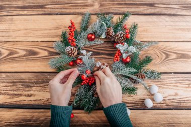 Kız Noel çelengini ahşap bir masada süslüyor..