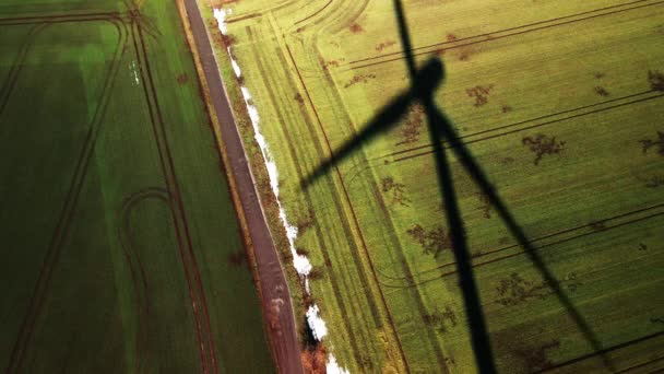 Luchtfoto van een veld met de draaiende schaduw van een windturbine — Stockvideo