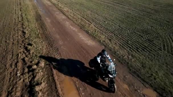 Drohne umfliegt Motorradfahrer, der auf schlammiger Straße unterwegs ist. — Stockvideo