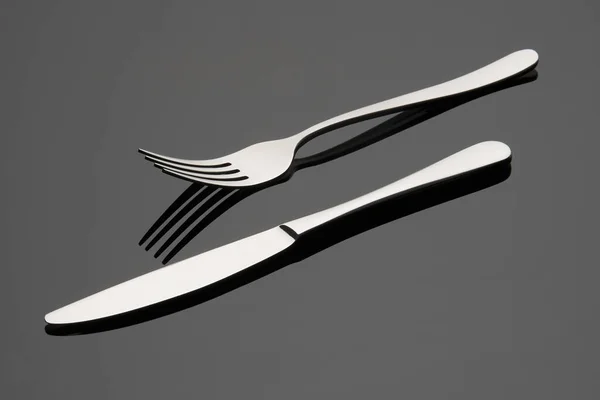 Nůž a vidlička na šedém pozadí. Příbory. Stock Obrázky