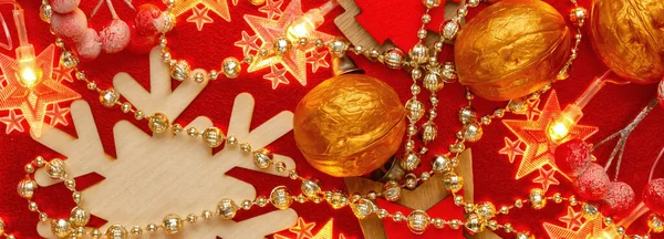 Pankart. Kırmızı ve altın arkaplanda Noel süsleri ve çelenkler var. Soyut Xmas deseni. Parlak altın boncuklar ve yıldız şeklinde sarı bir çelenk yeni yılın süsleri üzerine serilmiştir. Düz yatıyordu.