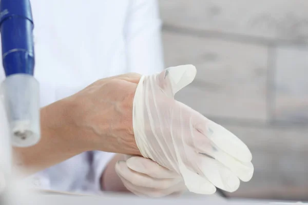 Profesyonel manikürcü beyaz tıbbi eldiven giyer. Manikür güzellik salonunda müşteri hizmetlerine hazırlanılıyor.