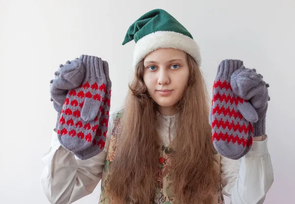 A girl in an elf hat holds several knitted mittens in her hands — Stock Photo, Image