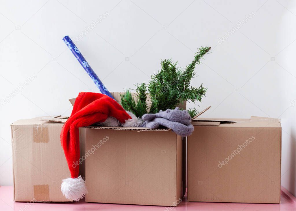 Three cardboard boxes one contains an artificial Christmas tree Santa hat and wrapping paper.