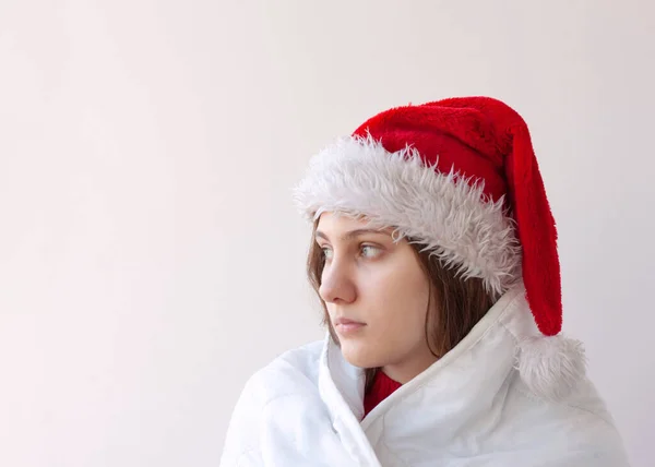 stock image A girl in a Santa hat wrapped in a white blanket face close-up