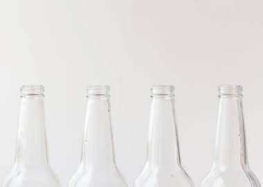 Beyaz arka planda dört boş şişe, boyuna yakın plan. Cam kap konsepti.