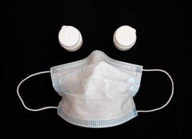 Used medical mask with two medicine bottles on a black background