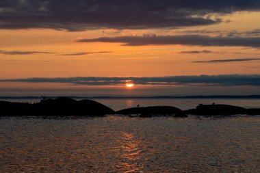 Sakin bir gölün üzerinde güzel bir gün batımı. Bulutlar arasındaki güneş ufkun ötesine geçer. Seyahat kavramı
