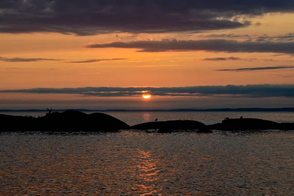 Sakin bir gölün üzerinde güzel bir gün batımı. Bulutlar arasındaki güneş ufkun ötesine geçer. Seyahat kavramı