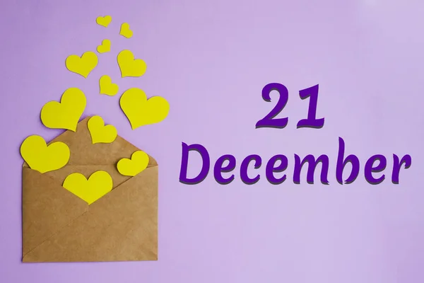 Sobre artesanal marrón con corazones amarillos sobre fondo lila e inscripción 21 de diciembre, concepto festivo. — Foto de Stock