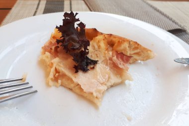 Çatal ve bıçakla beyaz tabakta bir dilim pizza.