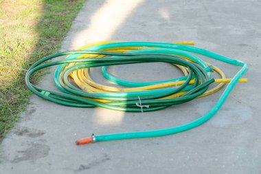 Arka bahçede yeşil ve sarı hortumlar var. Bahçe konsepti, yatay fotoğraf