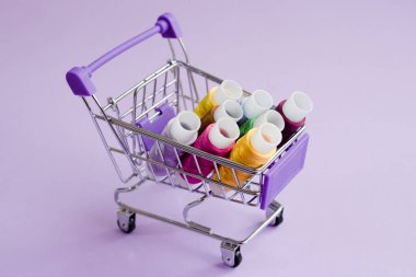 Tekerlekli leylak alışveriş arabasında renkli ipek iplikler. Süpermarket ekipmanları yakın çekim