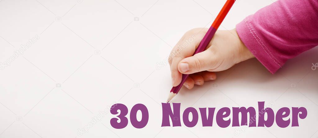 A child's hand writes 30 november in lilac pencil. Banner with copy space