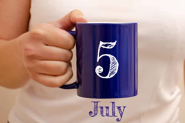 Blue cup 5 Temmuz 'daki yazı. Kupa kadının elinde, iş konsepti.
