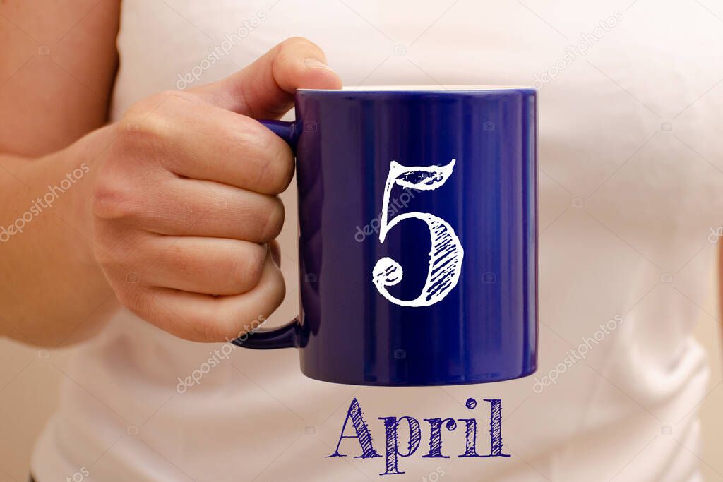 The inscription on blue cup 5 april. Cup in female hand, business concept
