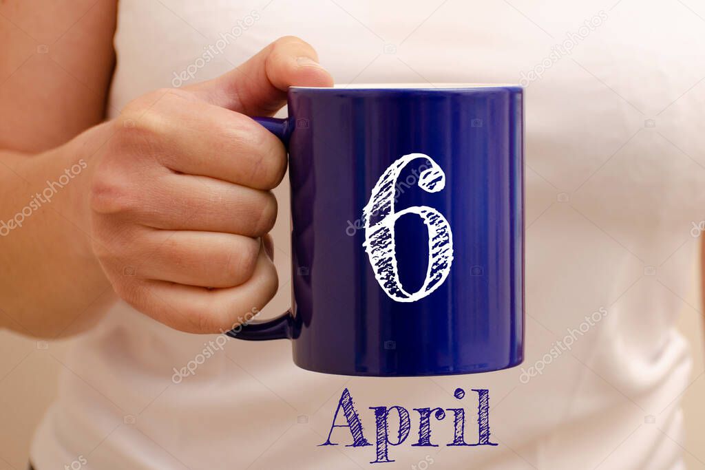 The inscription on blue cup 6 april. Cup in female hand, business concept