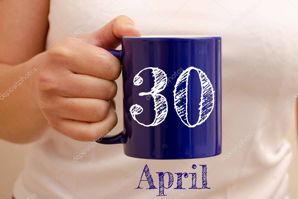 The inscription on blue cup 30 april. Cup in female hand, business concept