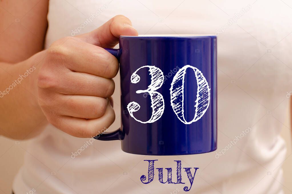 The inscription on blue cup 30 july. Cup in female hand, business concept