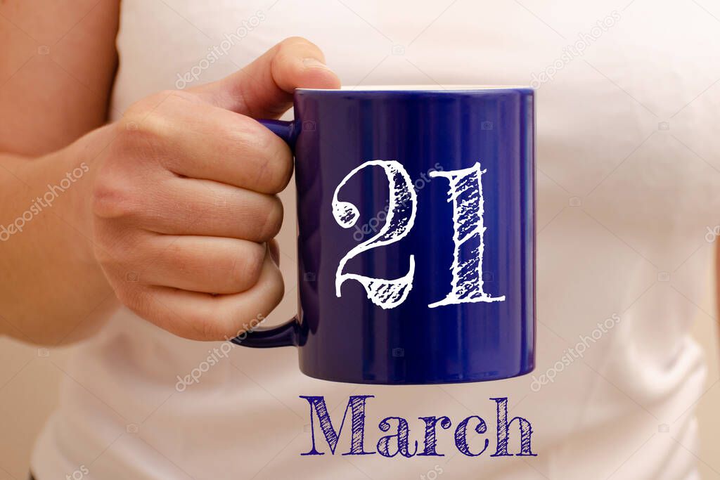 The inscription on blue cup 21 march. Cup in female hand, business concept