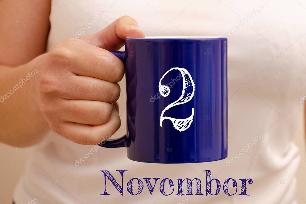 The inscription on blue cup 2 november. Cup in female hand, business concept