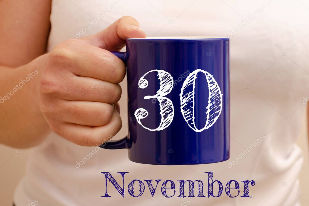The inscription on blue cup 30 november. Cup in female hand, business concept