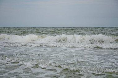 Dalga kıyıya vurdu, beyaz köpük damlaları, yaz bulutlu bir gün, tatil konsepti