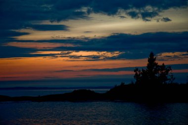 Ladoga Gölü üzerinde, Karelia 'da gün batımı. Bulutlu mavi bir gökyüzünün yatay fotoğrafı. Güneş ufukta batıyor.