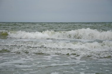 Dalga kıyıya vurdu, beyaz köpük damlaları, yaz bulutlu bir gün, tatil konsepti