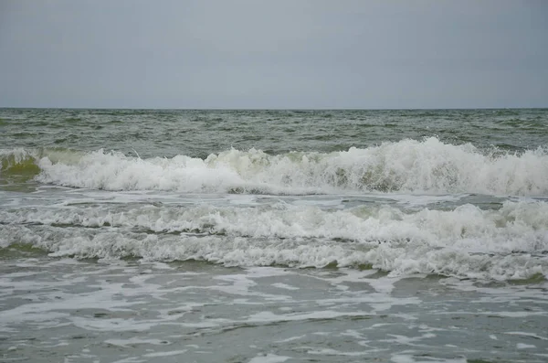 Dalga kıyıya vurdu, beyaz köpük damlaları, yaz bulutlu bir gün, tatil konsepti