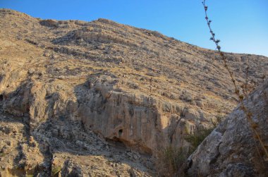 Wadi Kelt ya da Nahal Prat, İsrail 'in Yahudi Çölü' nde. Kayalıkların manzarası ve mağaradan mavi gökyüzü.