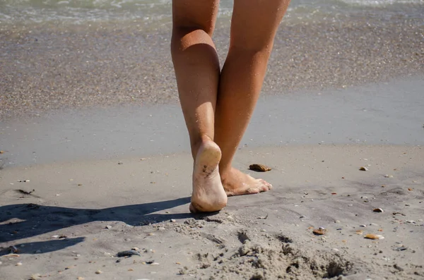 Women\'s feet walk on sea sand on a sunny summer day. Relaxation and wellness concept