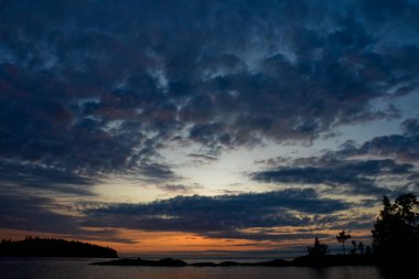 Gölün üzerinde günbatımı alacakaranlığı. Bulutlarda mavi gökyüzü, güzel doğanın yatay fotoğrafı.