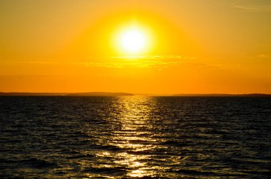 Gölün üzerinde parlak gün batımı. Turuncu güneş. Güneşli yol sakin sularda